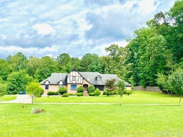 tudor-style house featuring a front yard and fence