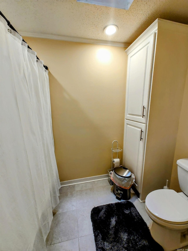 full bathroom featuring toilet, a shower with curtain, a textured ceiling, tile patterned flooring, and baseboards