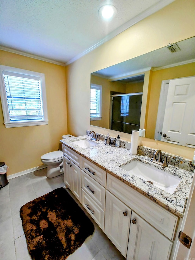 bathroom featuring a shower stall, double vanity, crown molding, and a sink