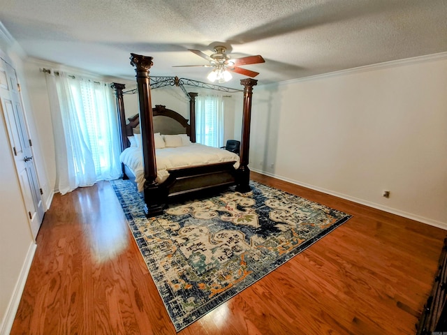 bedroom featuring crown molding, a textured ceiling, multiple windows, and wood finished floors