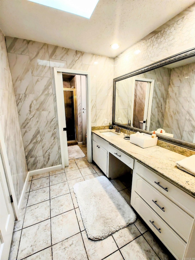 full bathroom with a stall shower, tile patterned floors, vanity, and tile walls