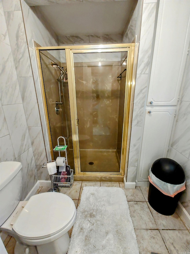 bathroom featuring tile walls, toilet, tile patterned floors, and a shower stall