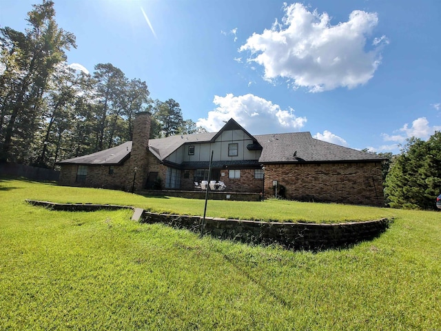 rear view of house with brick siding and a yard