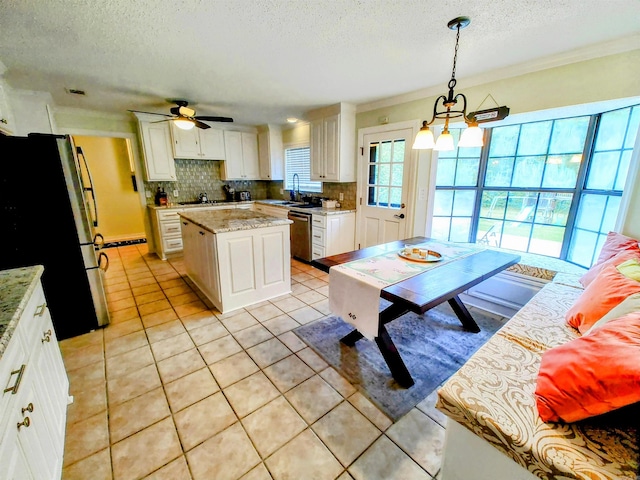 kitchen with tasteful backsplash, light tile patterned floors, stainless steel appliances, ceiling fan with notable chandelier, and white cabinets