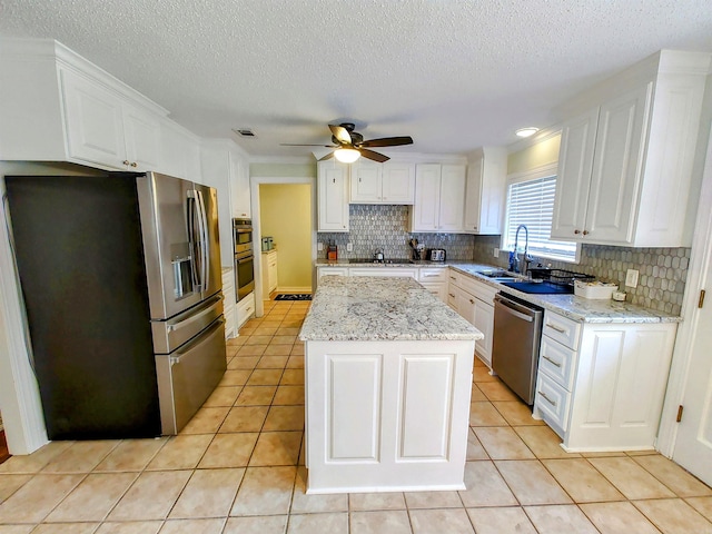 kitchen featuring white cabinetry, stainless steel appliances, a kitchen island, light tile patterned flooring, and ceiling fan