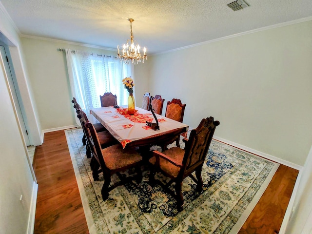 dining area with ornamental molding, a notable chandelier, and wood finished floors