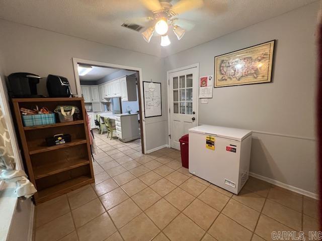 kitchen with ceiling fan, light tile patterned flooring, a textured ceiling, fridge, and white cabinets