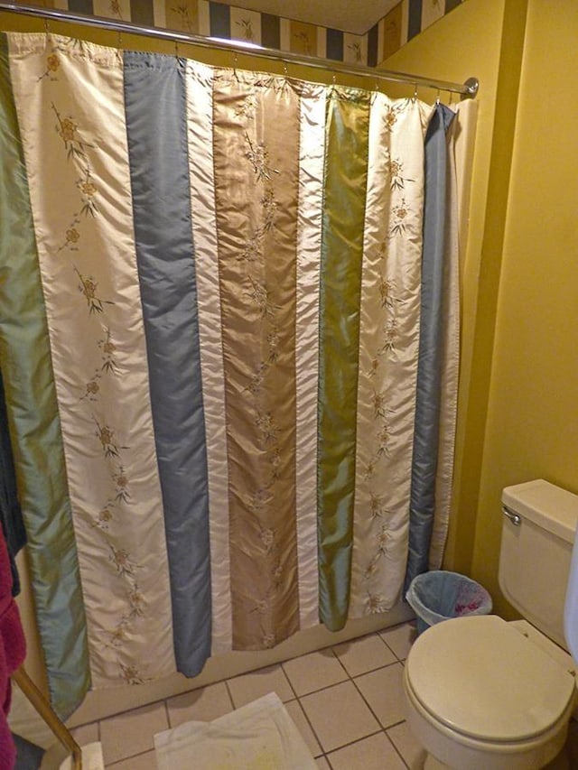 bathroom featuring toilet, tile patterned floors, and curtained shower