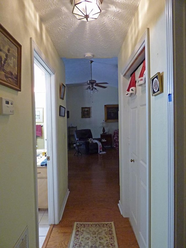 hall featuring a textured ceiling and light hardwood / wood-style flooring