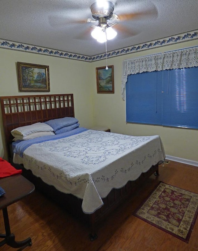 bedroom with a textured ceiling, hardwood / wood-style flooring, and ceiling fan