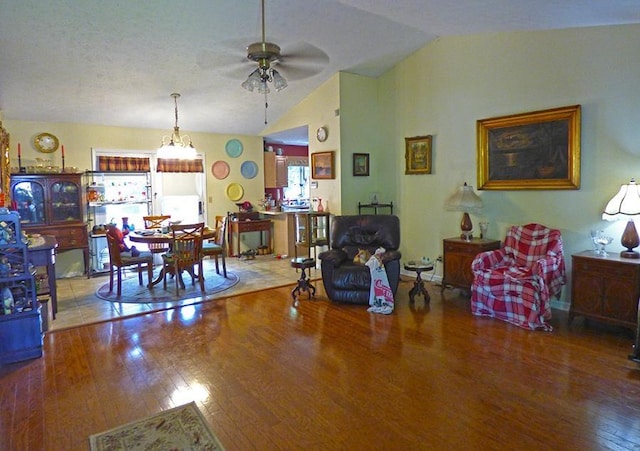 living room with ceiling fan, wood-type flooring, and vaulted ceiling