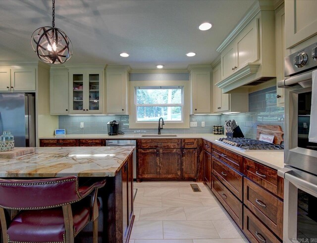 kitchen featuring light stone countertops, sink, hanging light fixtures, stainless steel appliances, and decorative backsplash