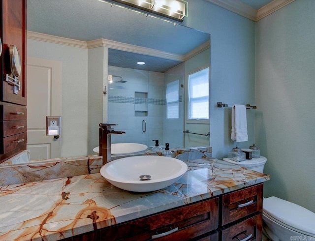 bathroom featuring vanity, toilet, a shower with shower door, and crown molding