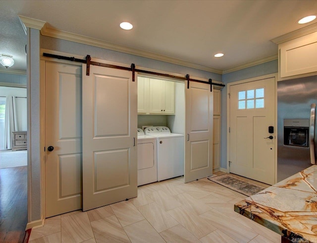 laundry room with cabinets, a barn door, washing machine and dryer, ornamental molding, and a healthy amount of sunlight