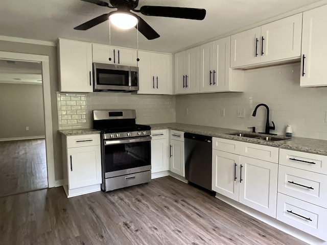 kitchen featuring white cabinets, sink, hardwood / wood-style flooring, tasteful backsplash, and stainless steel appliances