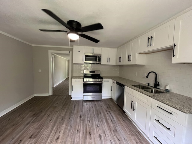 kitchen with decorative backsplash, appliances with stainless steel finishes, sink, white cabinets, and dark hardwood / wood-style floors