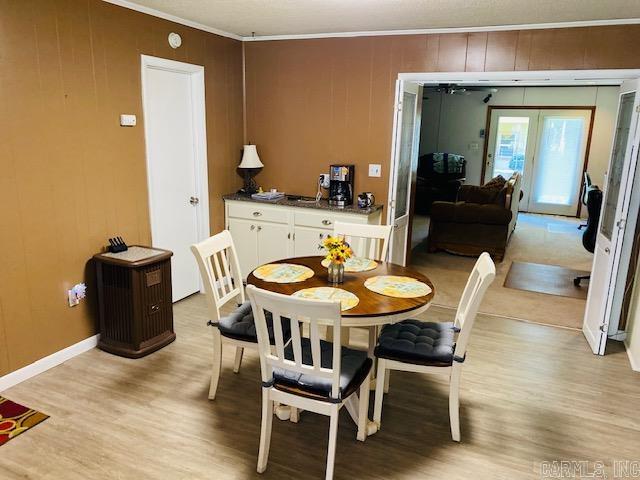 dining area with light hardwood / wood-style floors, french doors, ornamental molding, and wooden walls