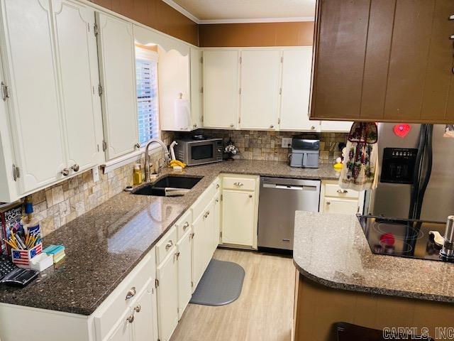 kitchen with sink, white cabinetry, stainless steel appliances, and dark stone counters