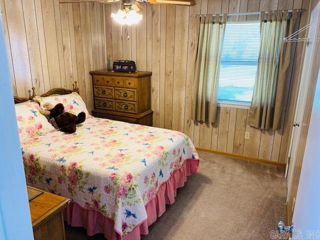 carpeted bedroom featuring wooden walls