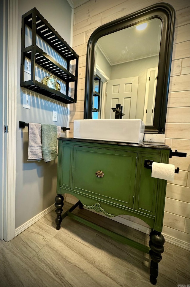 bathroom with wood walls, hardwood / wood-style floors, vanity, and crown molding