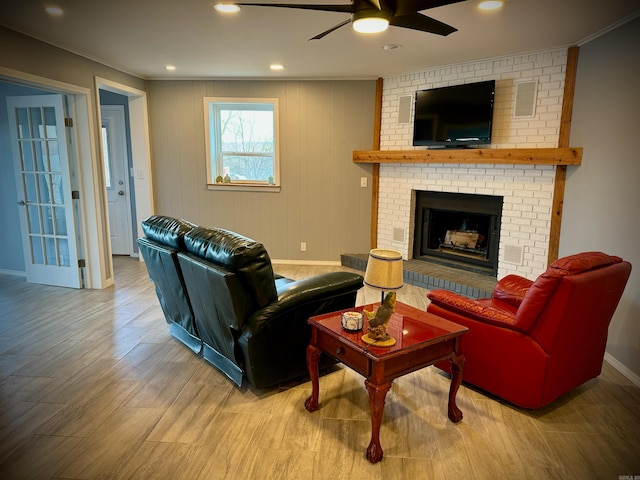 living room featuring brick wall, hardwood / wood-style floors, ceiling fan, and a fireplace