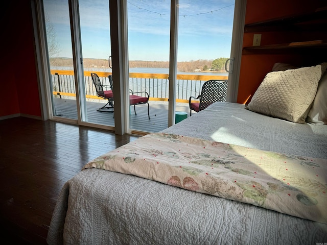 bedroom featuring a water view, dark hardwood / wood-style floors, and access to outside