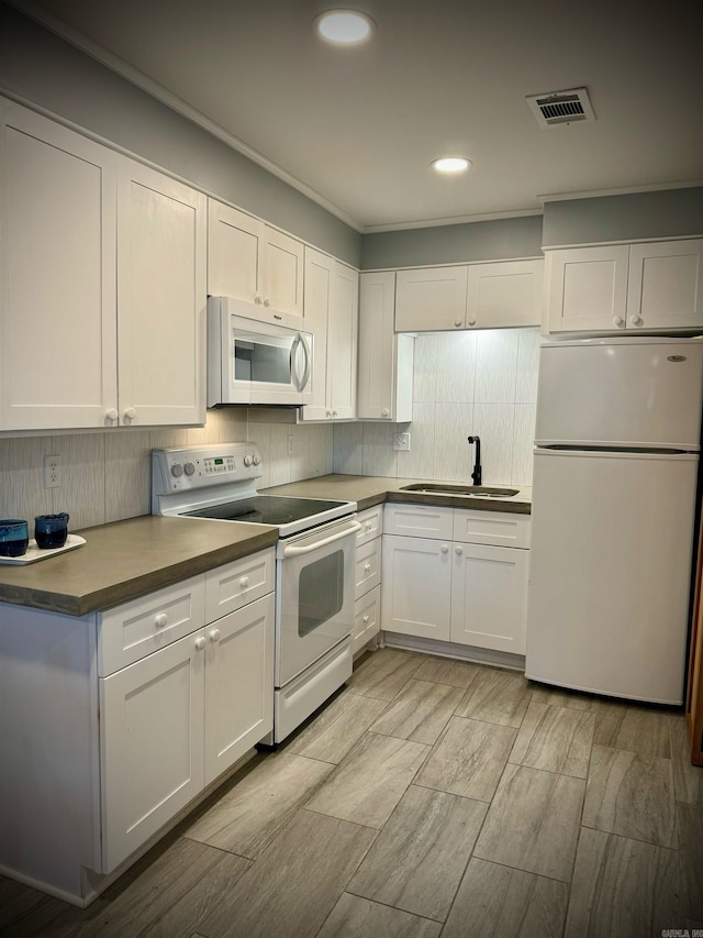 kitchen featuring sink, white appliances, white cabinetry, and backsplash