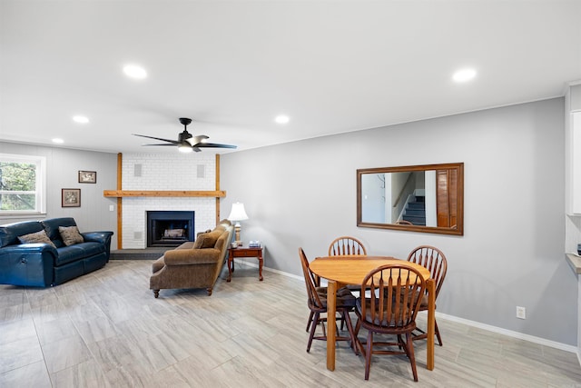 dining room with ceiling fan, a fireplace, and brick wall