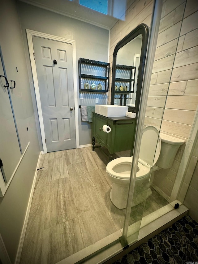 bathroom featuring a shower with door, tile flooring, toilet, and vanity