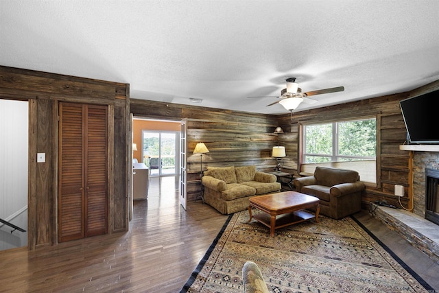 170 Ridge Rd, Houston, AR 72720 - living area with rustic walls, hardwood / wood-style floors, a stone fireplace, ceiling fan, and a textured ceiling