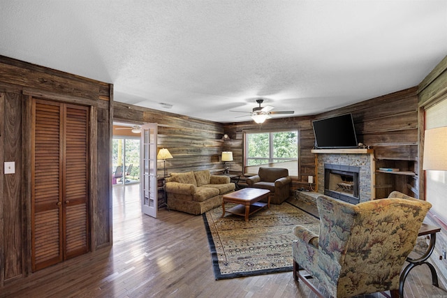 170 Ridge Rd, Houston, AR 72720 - living area featuring a ceiling fan, a textured ceiling, wood walls, and a stone fireplace