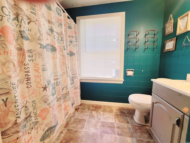 bathroom featuring a shower with shower curtain, vanity, toilet, and tile walls