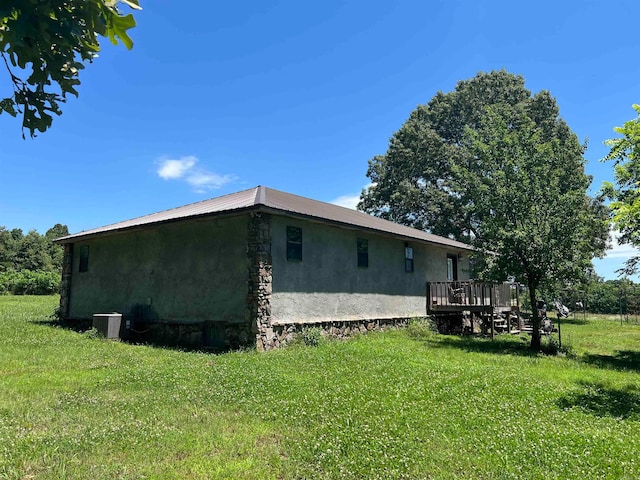 view of side of property featuring a deck, a lawn, and cooling unit