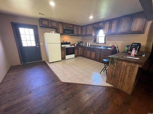 kitchen featuring white appliances, a healthy amount of sunlight, tile counters, and light hardwood / wood-style floors