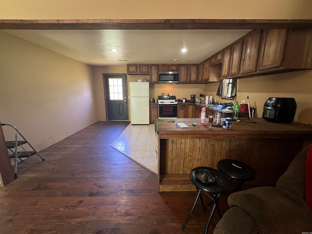 kitchen with kitchen peninsula, hardwood / wood-style flooring, and white appliances