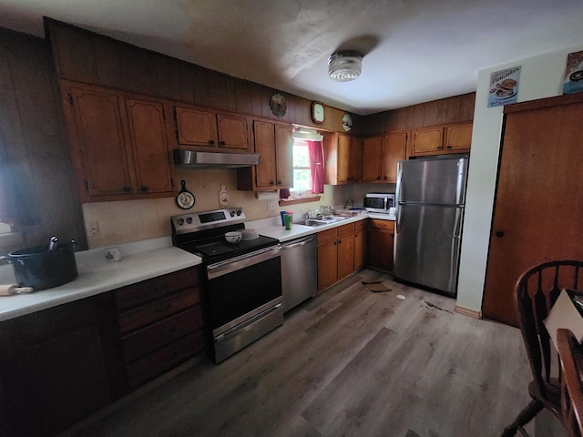 kitchen with appliances with stainless steel finishes, light hardwood / wood-style flooring, and sink