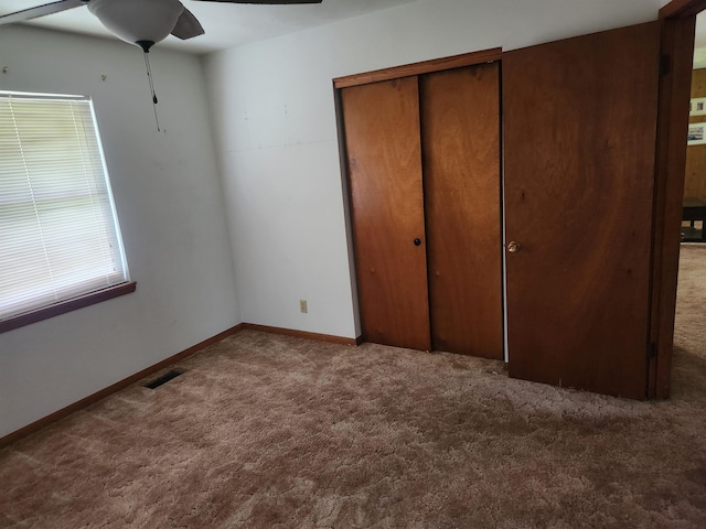 unfurnished bedroom featuring dark colored carpet, ceiling fan, a closet, and multiple windows