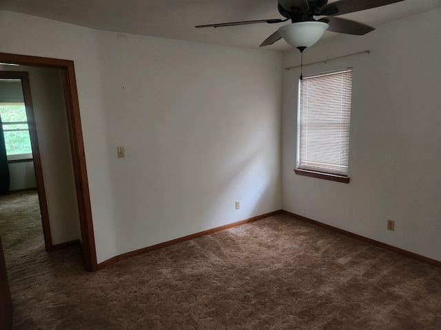 spare room with ceiling fan and dark carpet