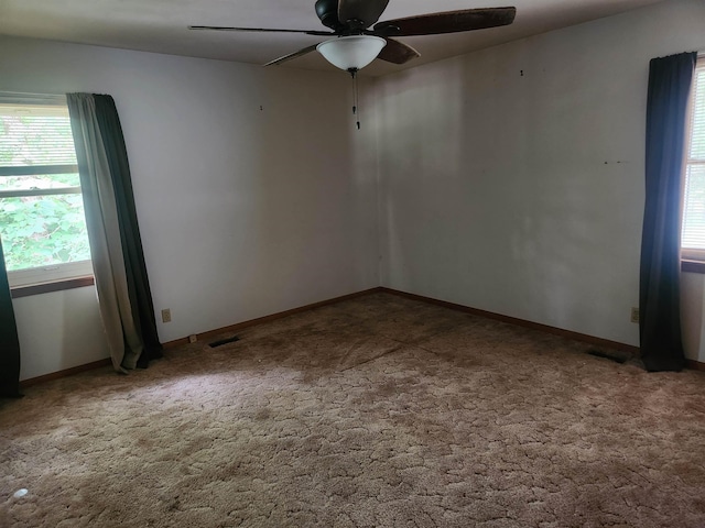 carpeted spare room featuring plenty of natural light and ceiling fan