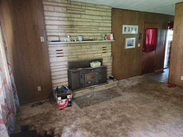 carpeted living room featuring a wood stove and wood walls