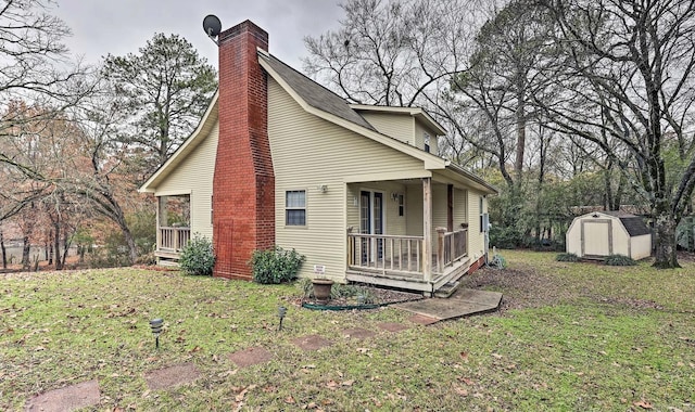 rear view of property featuring covered porch, a storage shed, and a yard