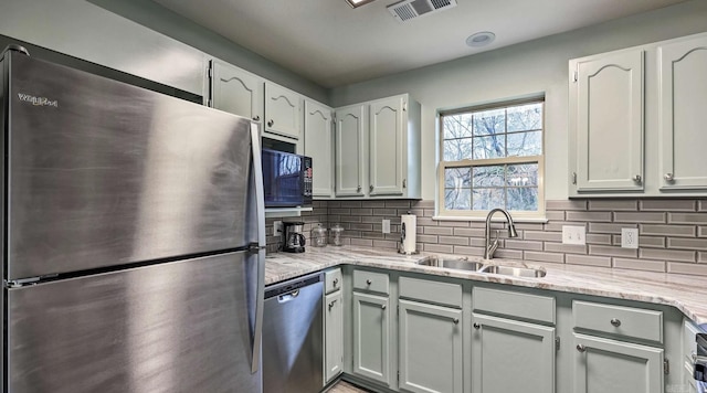 kitchen featuring white cabinets, appliances with stainless steel finishes, decorative backsplash, and sink