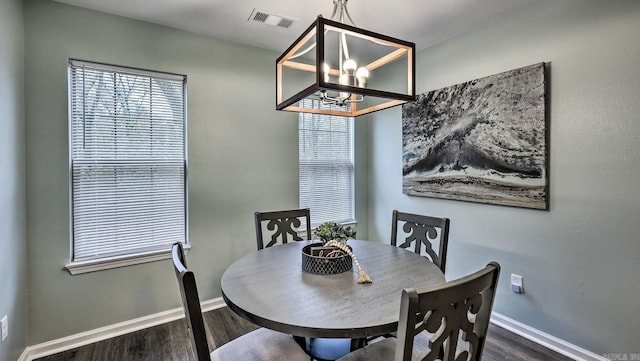 dining space with dark hardwood / wood-style floors and an inviting chandelier