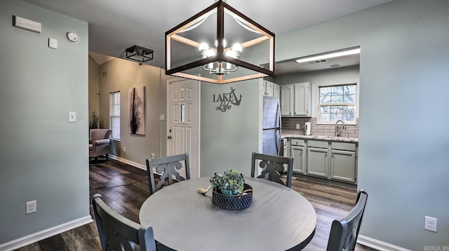 dining area featuring dark hardwood / wood-style flooring, sink, and a notable chandelier