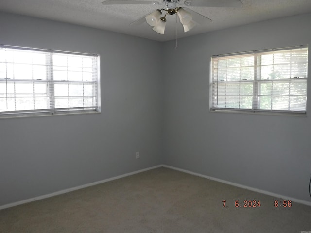 carpeted spare room with ceiling fan and a textured ceiling