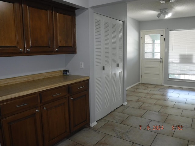 kitchen featuring light tile patterned flooring, dark brown cabinetry, a textured ceiling, and a wealth of natural light