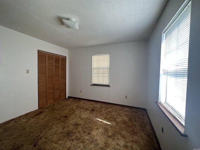 unfurnished bedroom with a closet, a textured ceiling, and dark colored carpet