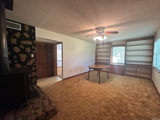 carpeted office space featuring ceiling fan and a textured ceiling