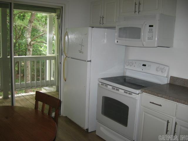 kitchen with white cabinets, dark hardwood / wood-style floors, and white appliances