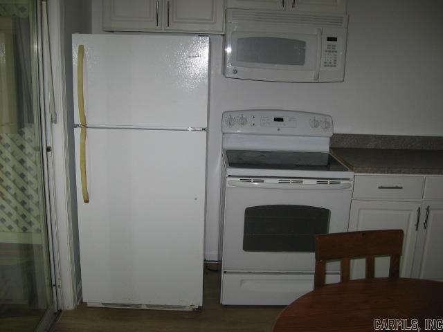 kitchen featuring dark hardwood / wood-style flooring, white cabinets, and white appliances